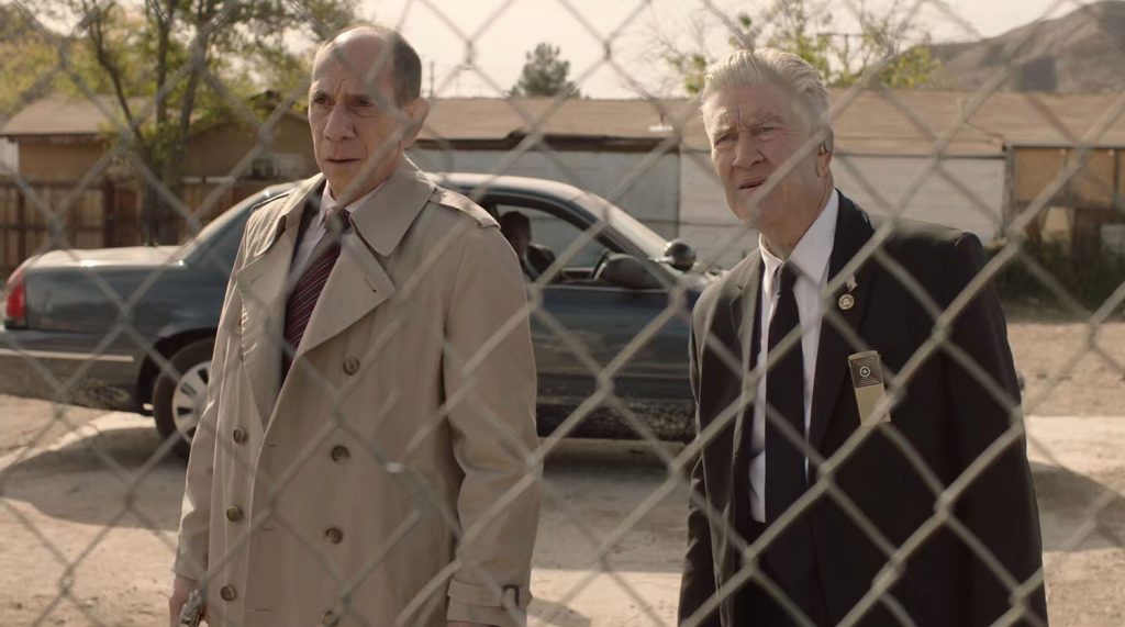 Albert Rosenfield and Gordon Cole looking through chain-link fence