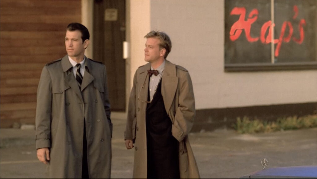 Agents Desmond and Stanley dressed in overcoats talk in the parking lot of Hap's Diner