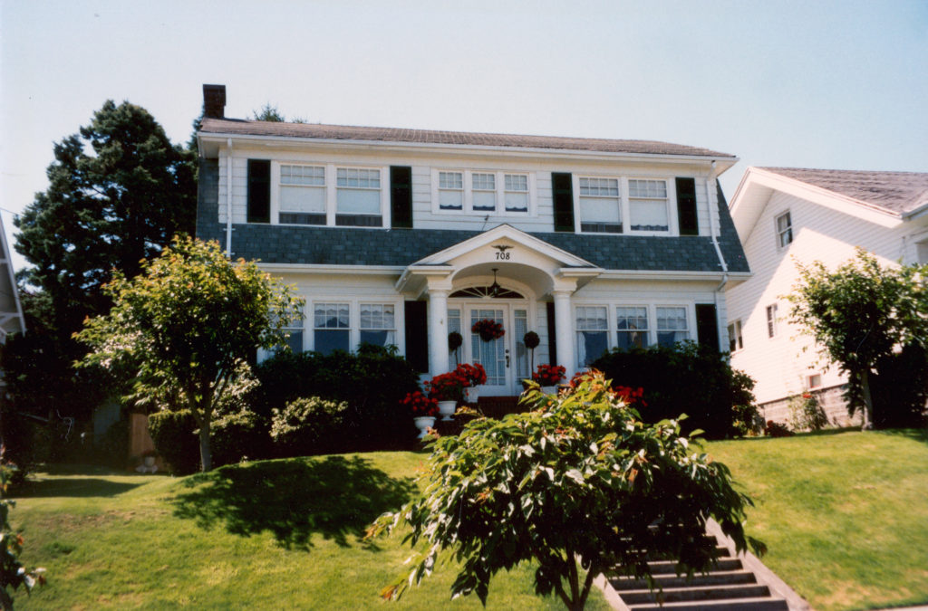 Front view of the Palmer House in Everett, Washington with trees along the street and concrete stairs leading to the front porch