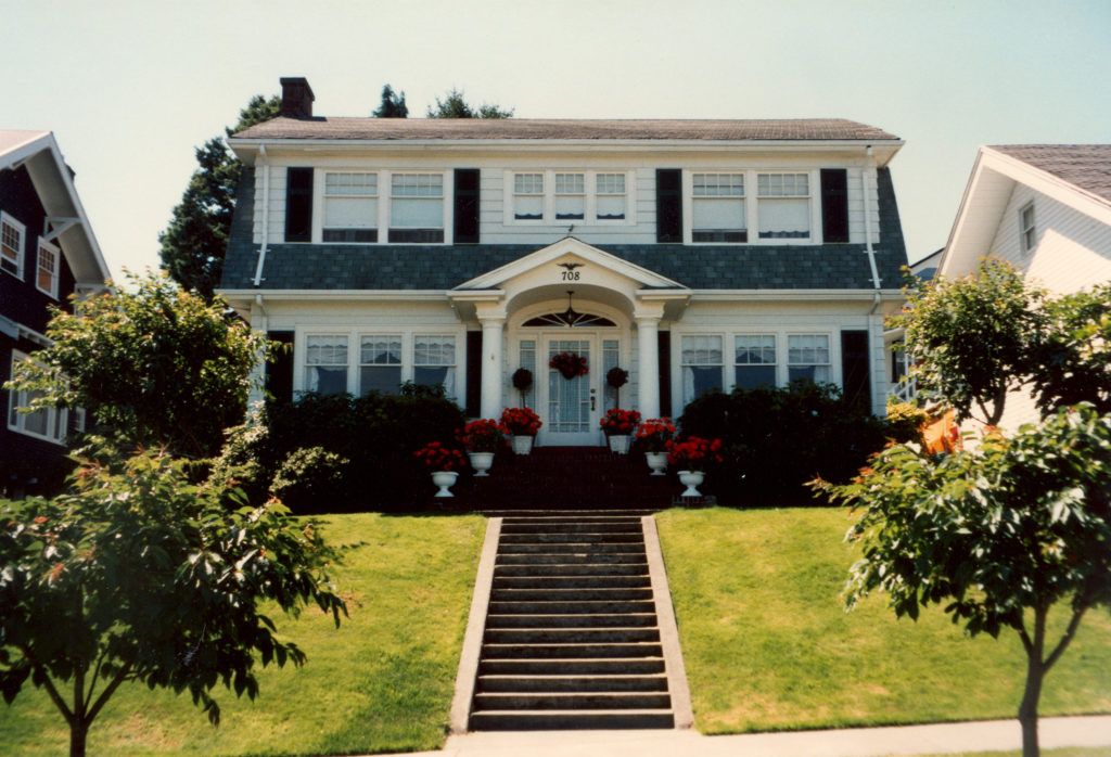 Front view of the Palmer House in Everett, Washington with trees along the street and concrete stairs leading to the front porch