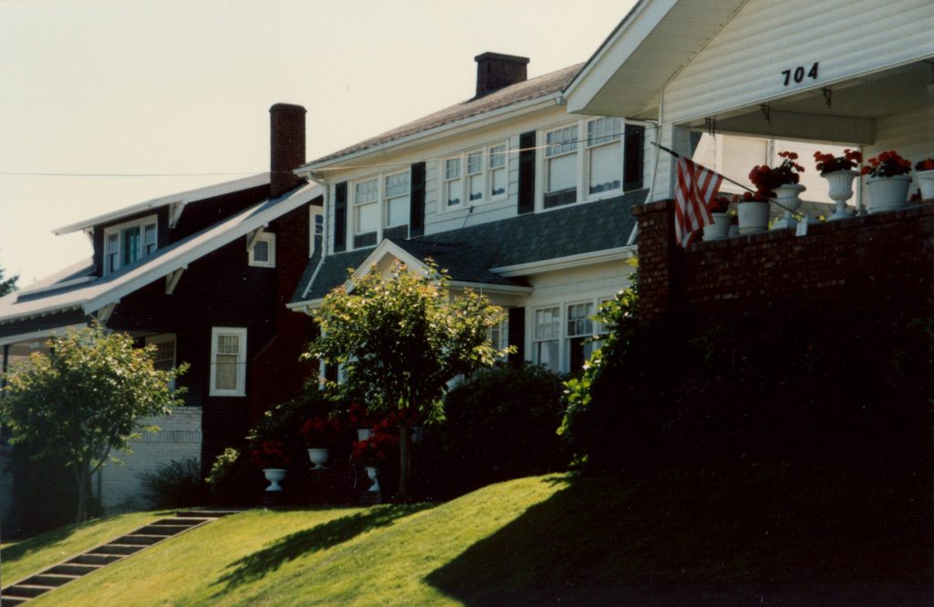 Front side view of the Palmer House in Everett, Washington with trees along the street and concrete stairs leading to the front porch