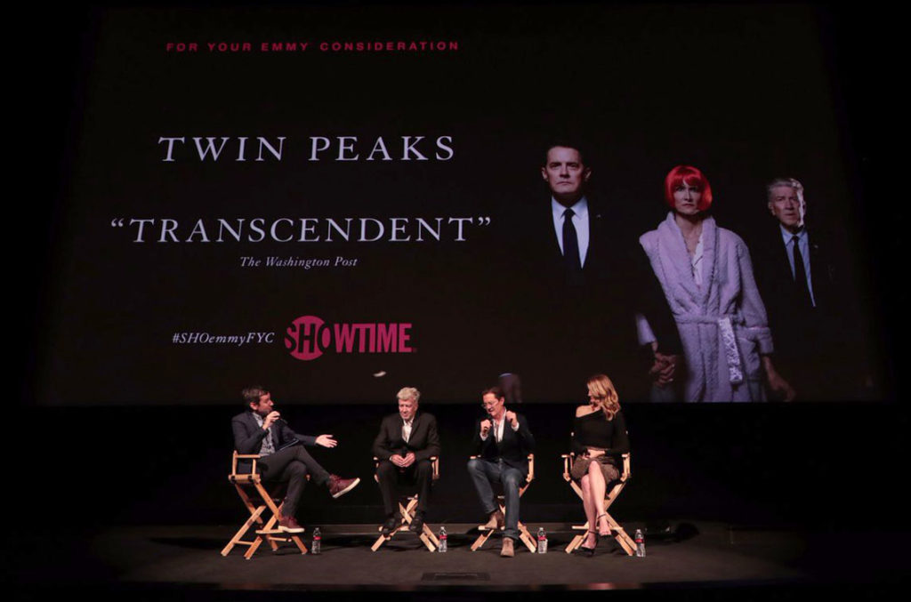 Four people sitting on a stage in director's chairs with a Twin Peaks advertisement on the screen.