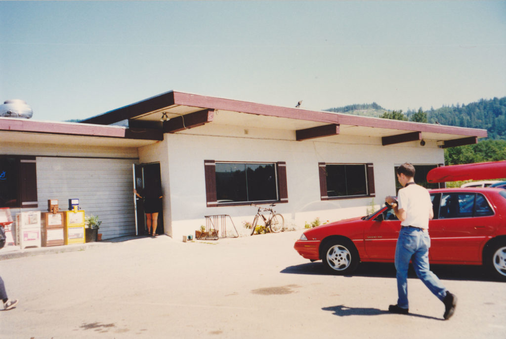 Exterior of Fall City Grill restaurant with a red car in the parking lot and a man walking toward the front door.