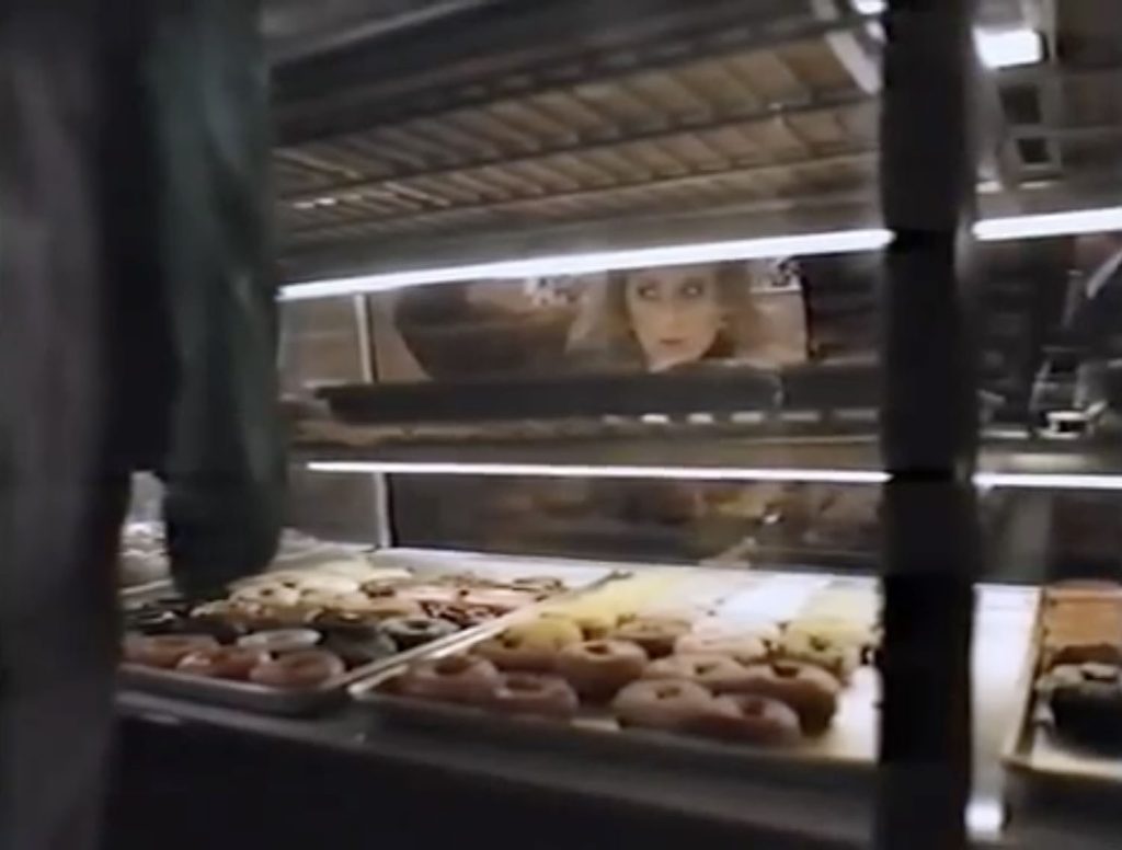 Lucy Moran looking into a counter with doughnuts