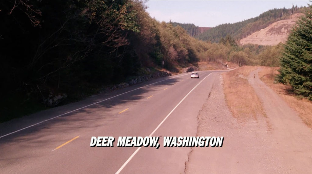A road with a car and a lower third title: "Deer Meadow, Washington"
