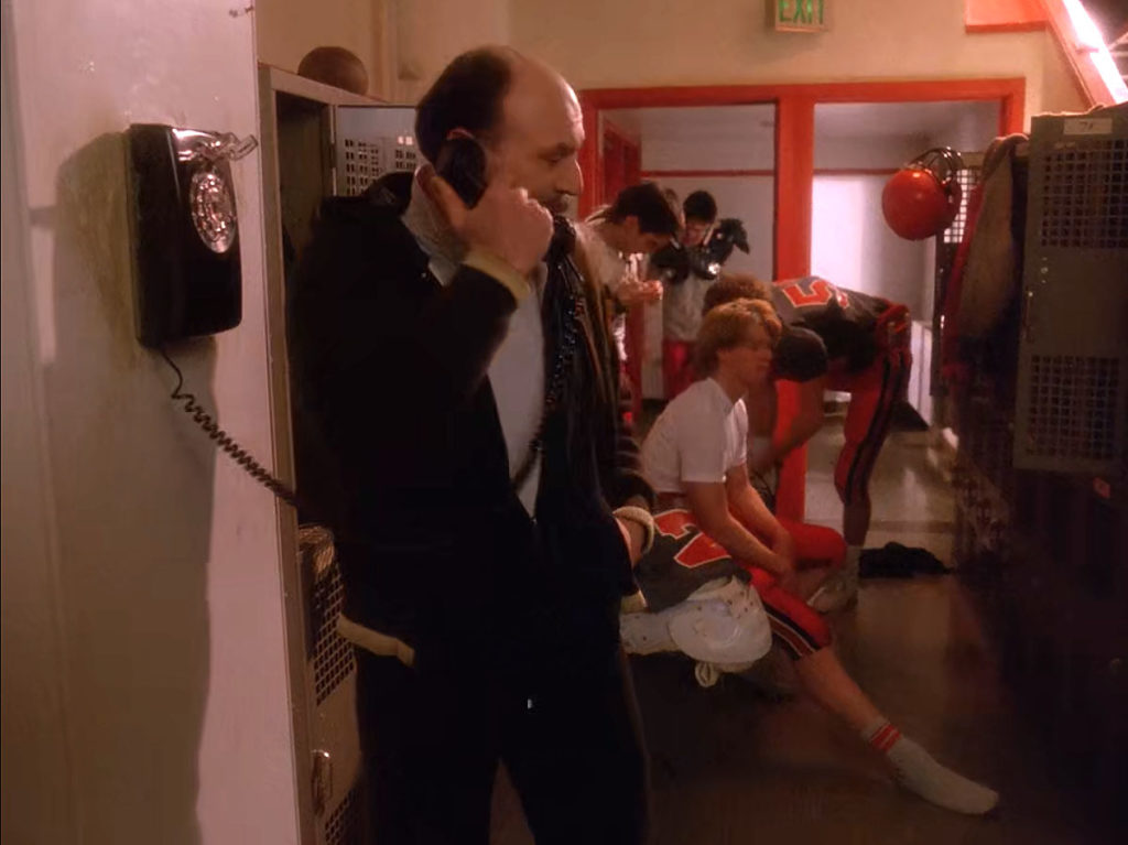 Football Coach on phone in Locker Room