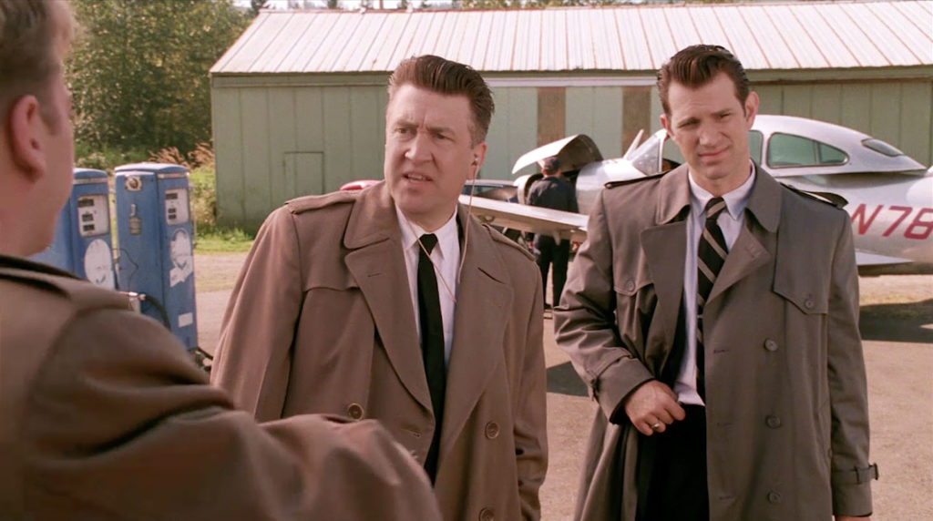 Three people having a conversation by a silver airplane