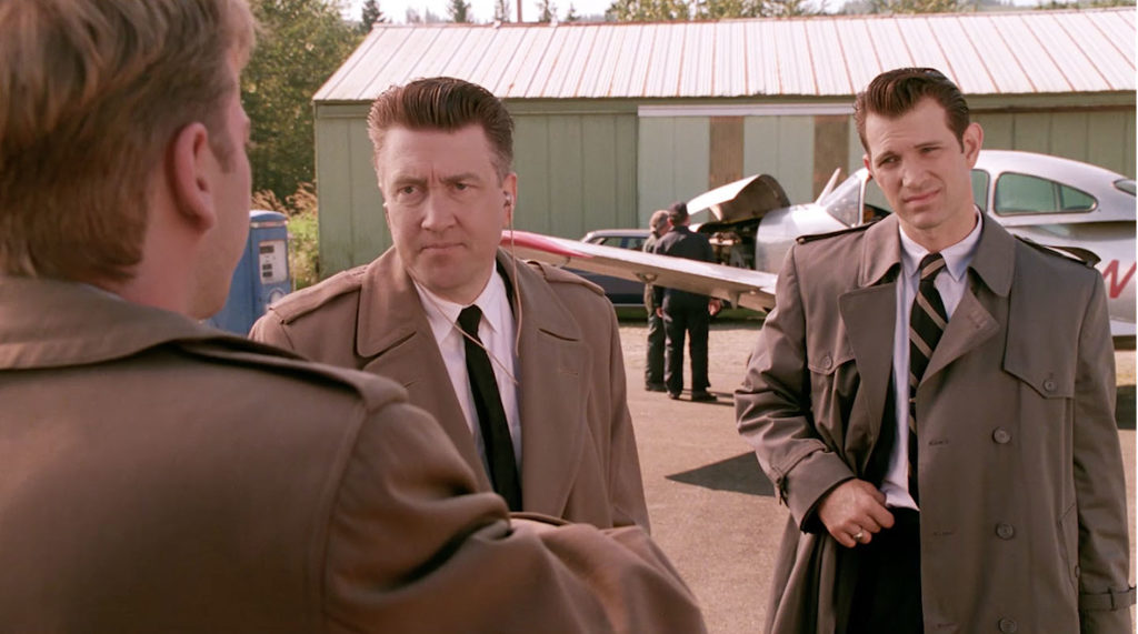 Three people having a conversation by a silver airplane