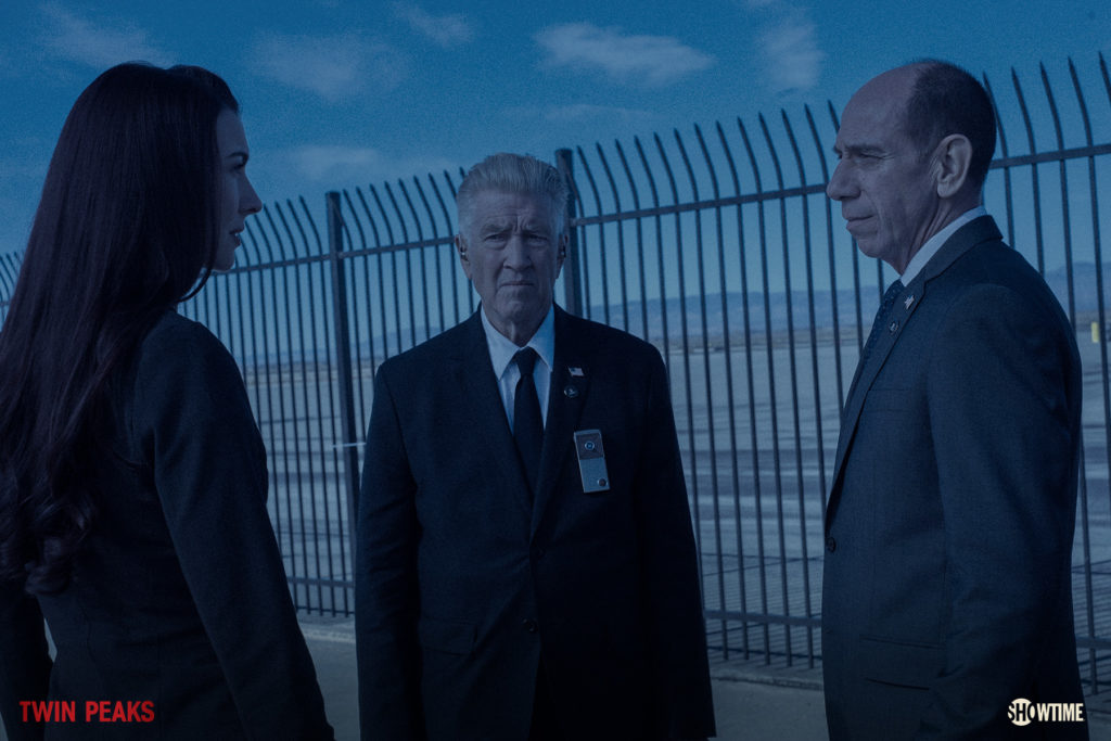 Three FBI agents talking by a metal fence at the airport