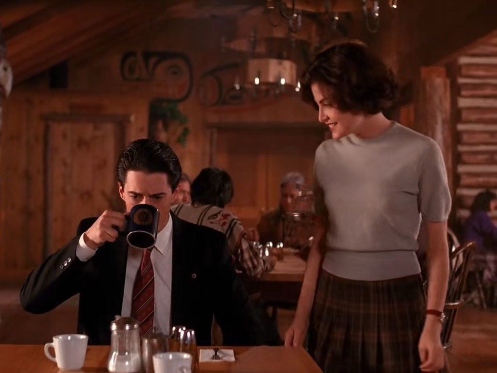 Audrey Horne speaks Special Agent Dale Cooper who is drinking coffee in The Great Northern Hotel dining room