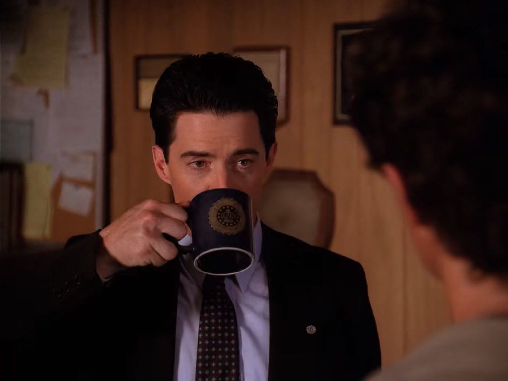 Special Agent Dale Cooper drinking coffee while listening to Sheriff Harry S. Truman in his office