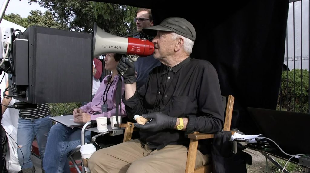 David Lynch speaking in a megaphone while Sabrina Sutherland looks on