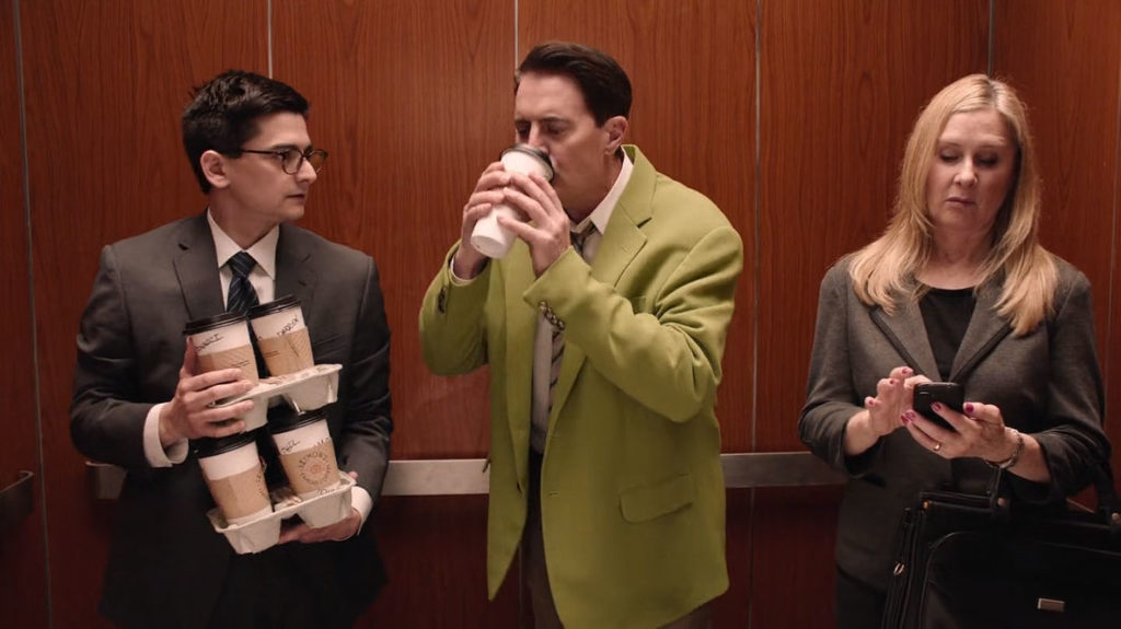 Dougie Jones drinking coffee while Phil holds extra cups in an elevator