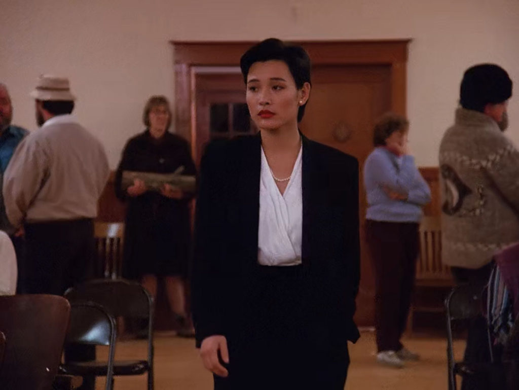 Josie Packard in a black suit with white blouse walks down the aisle