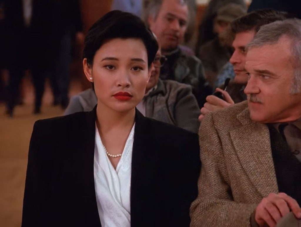 Josie Packard in a black suit with white blouse sits next to Pete Martell in a tan jacket 