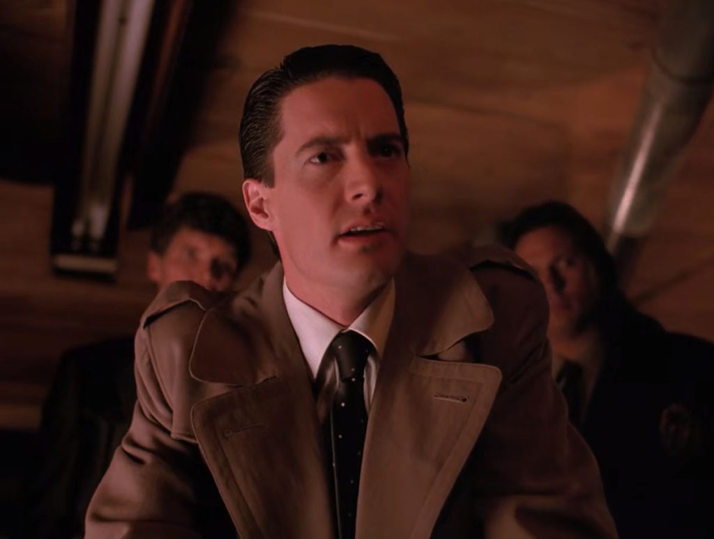 Agent Cooper leaning in with Big Ed and Deputy Hawk in the background