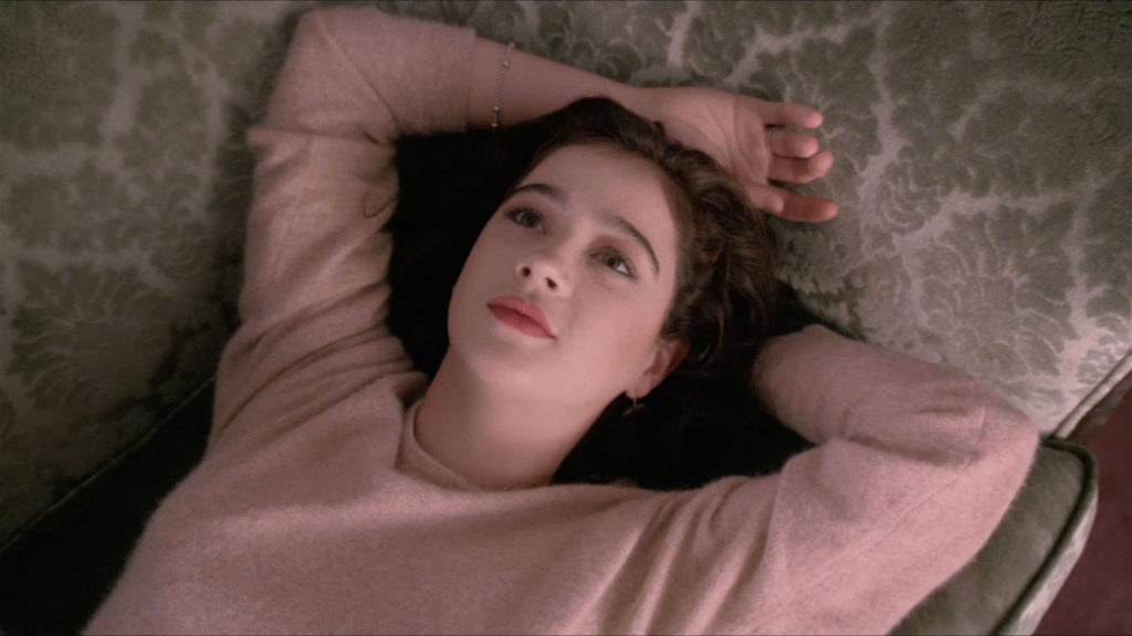 Donna Hayward laying on the couch with arms above her head