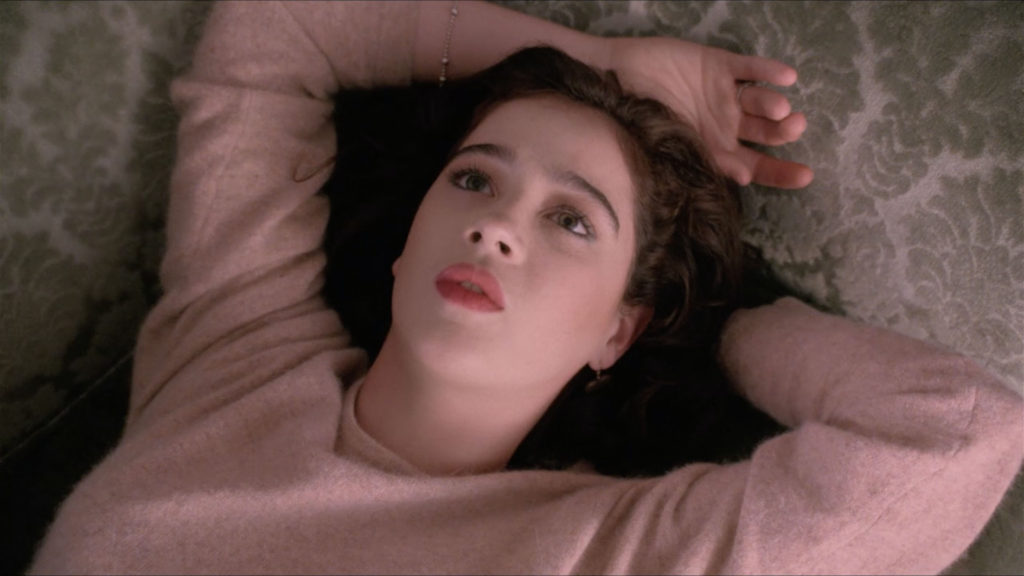 Donna Hayward with arms over her head laying on couch