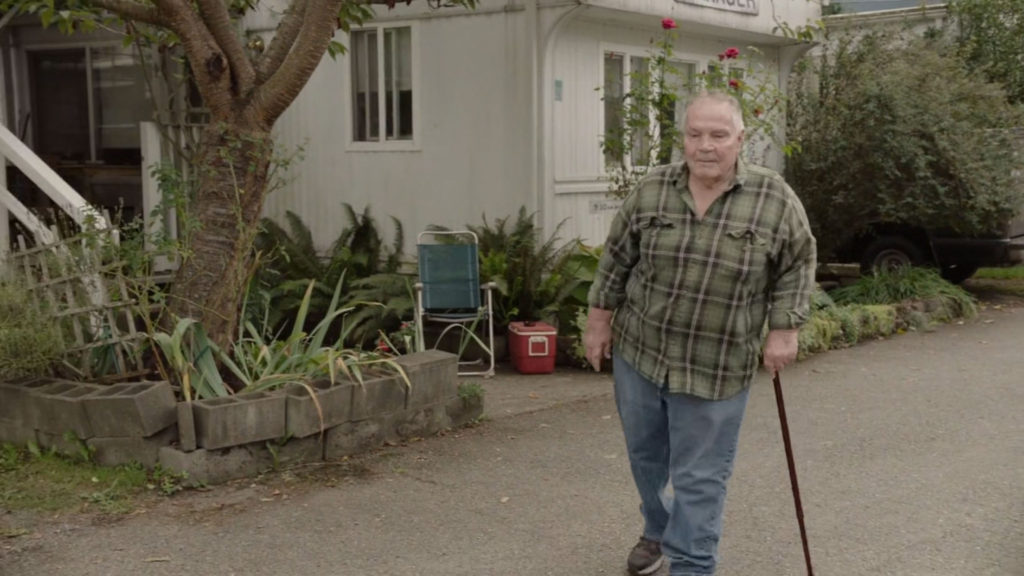 Guy walking with a cane in a trailer park