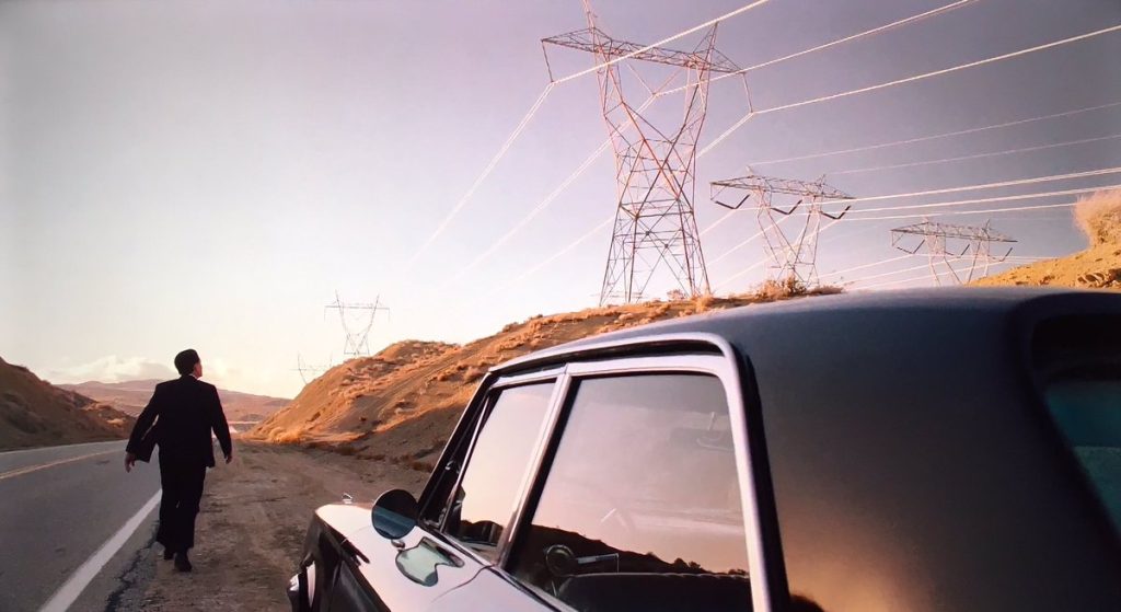 Cooper outside a vehicle looking at transmission towers