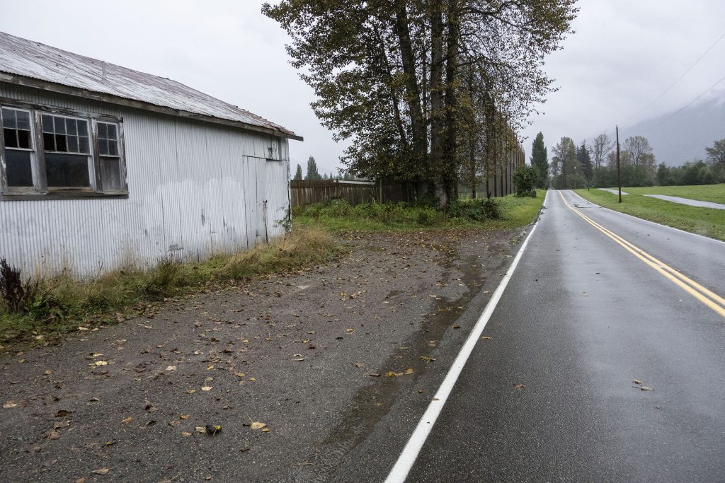 Abandoned building along side of a road with trees