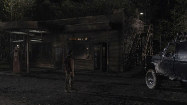 Convenience store location with Woodsman standing outside at night