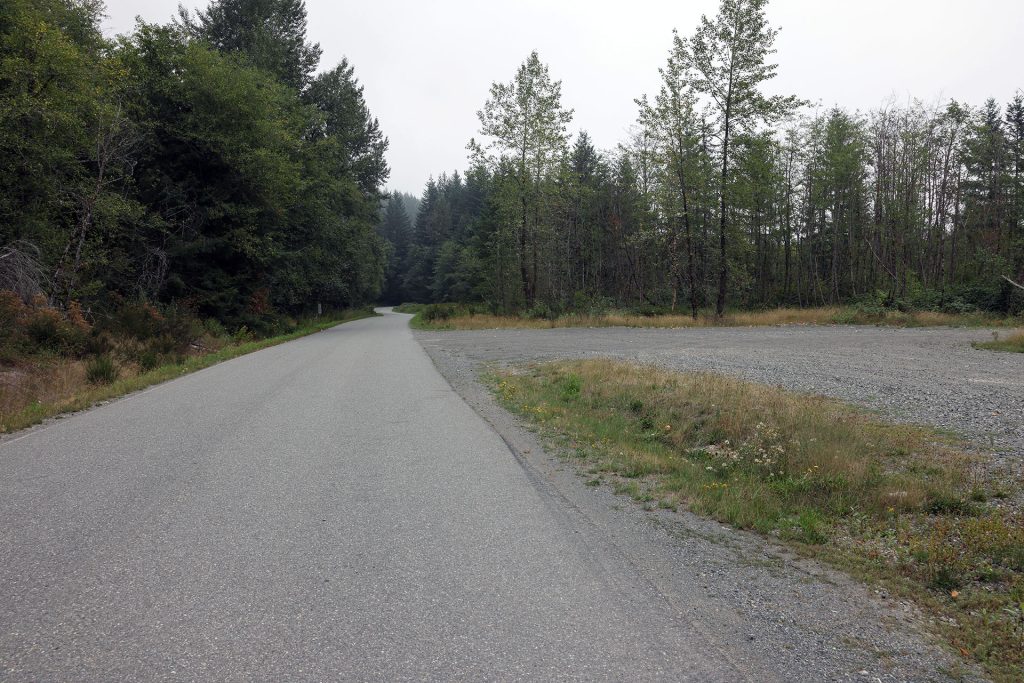 Road by gravel field lined with trees