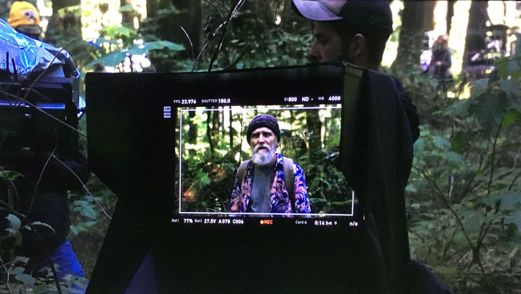 Jerry Horne sitting in the woods as seen through a monitor
