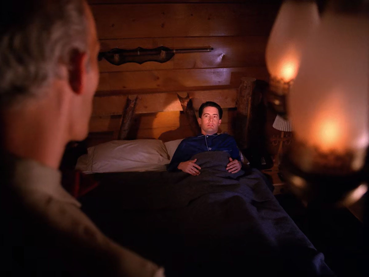 Agent Cooper laying in bed while the Giant speaks in his room.