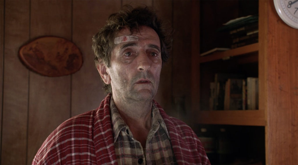 Carl Rodd (Harry Dean Stanton) in a red robe standing in Teresa Banks' trailer