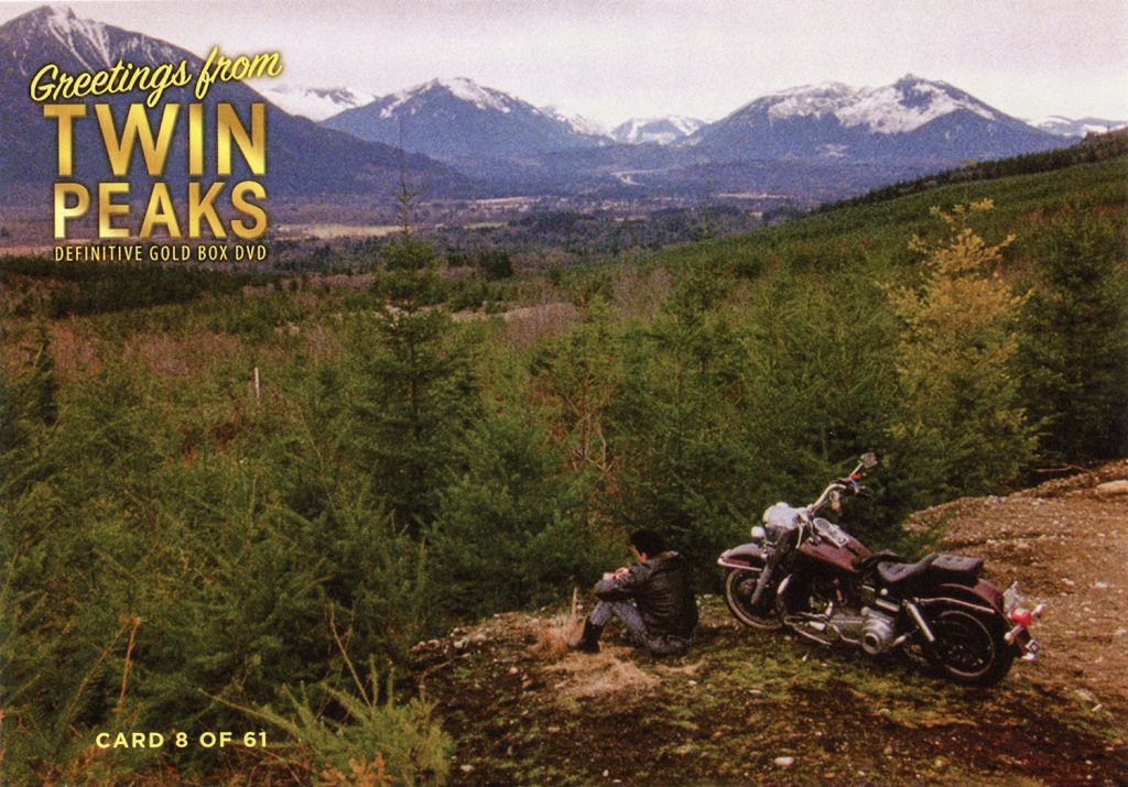 Greetings from Twin Peaks DVD postcards man sitting on hill with motorcycle looking at snow-covered mountains