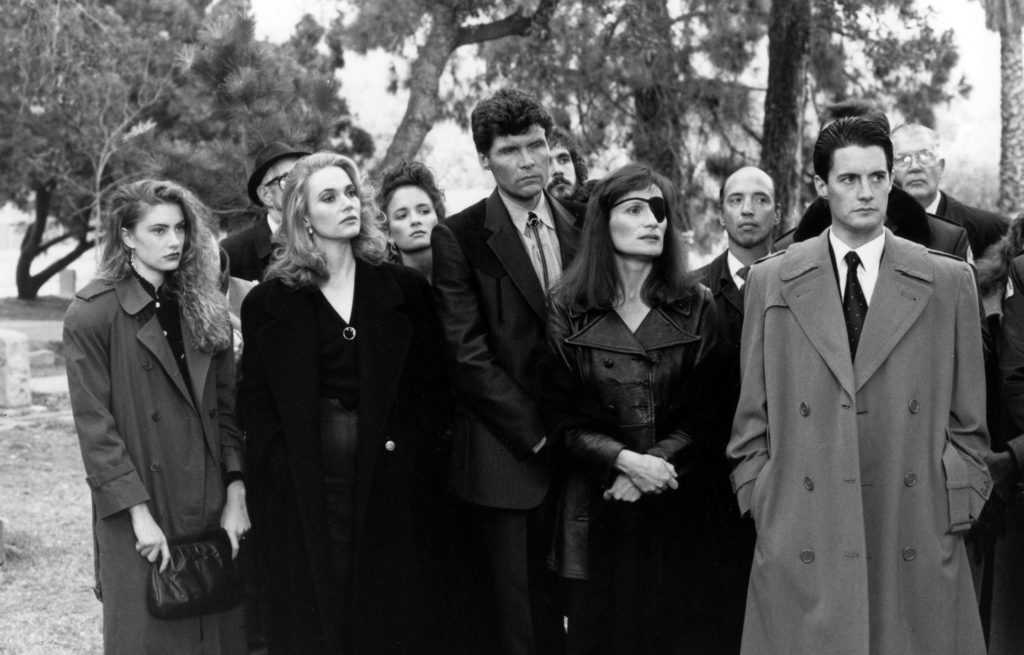 People standing in a line wearing overcoats at a cemetery