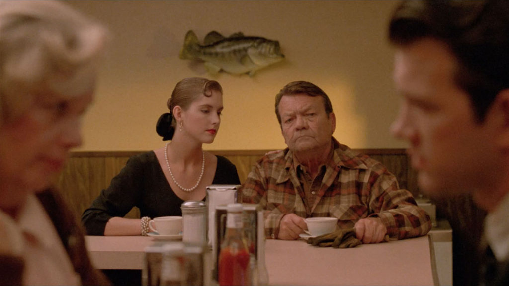 And old guy and a young woman sit at the end of a bar as seen between Irene and Agent Chet Desmond. A giant fish is on the wall directly behind the couple