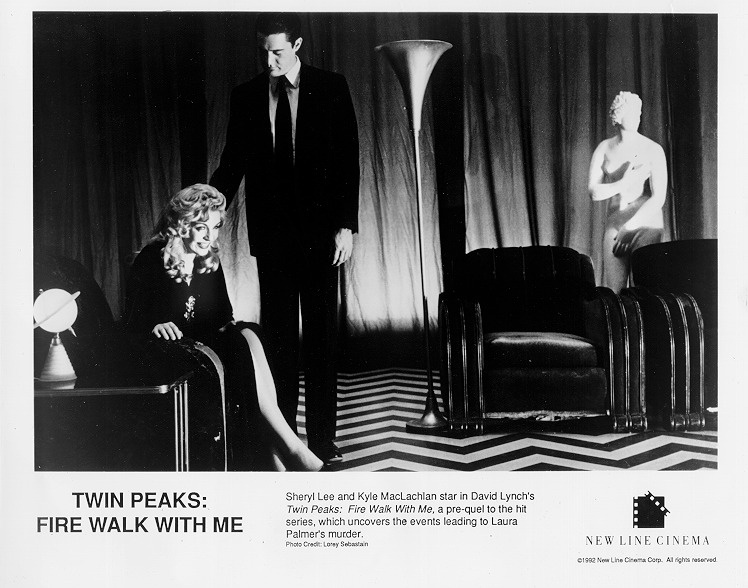 Black and white publicity image from Twin Peaks: Fire Walk With Me. Dale Cooper and Laura Palmer are in the Red Room. Laura is leaning forward and laughing while Cooper stands nearby