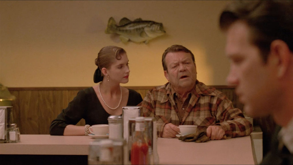The Old Guy and the French Girl sit at Hap's Diner. Agent Chet Desmond's face appears in the foreground.