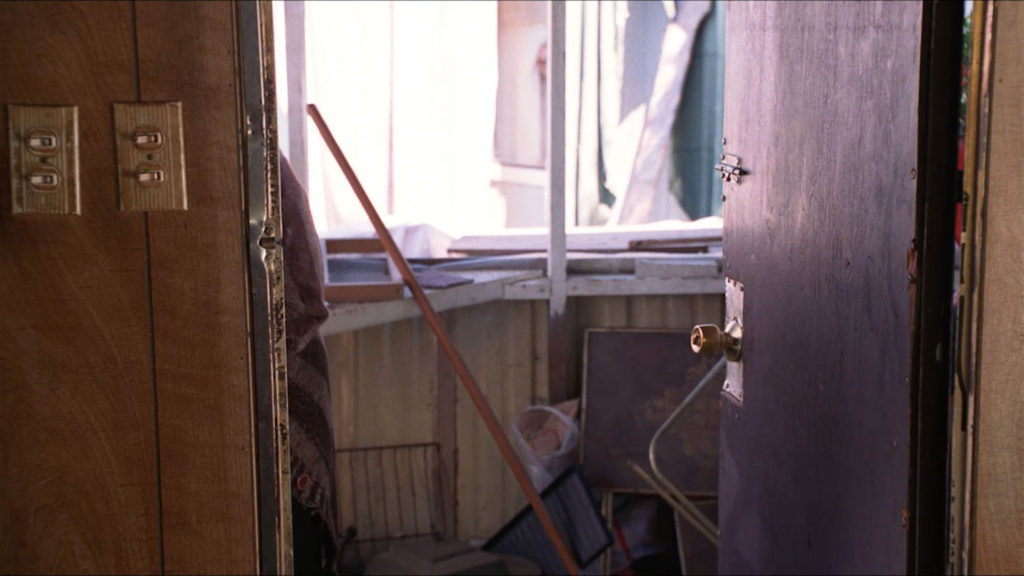Empty doorway at Teresa Banks' trailer with someone peeking through curtains in the trailer next door.