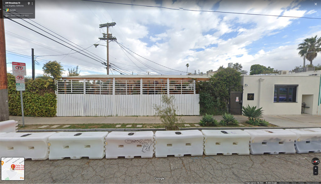 Google Street View image of a building with a fence on the side of the street