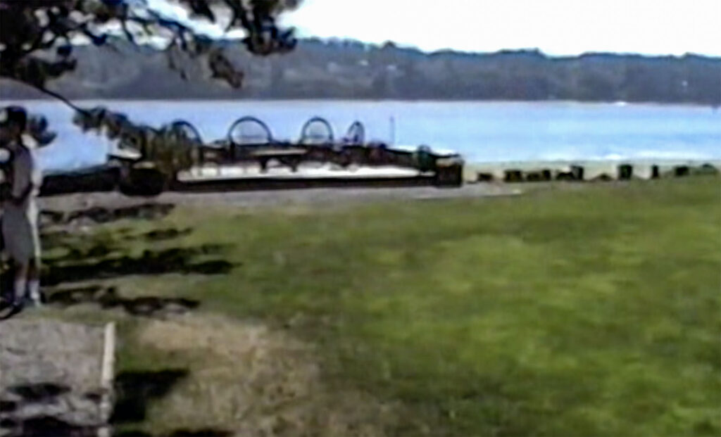Grainy image of the deck at Kiana Lodge with water in the distance.