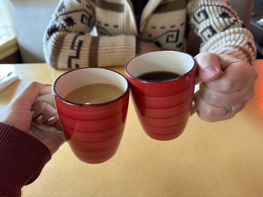 Two hands holding red cups of coffee