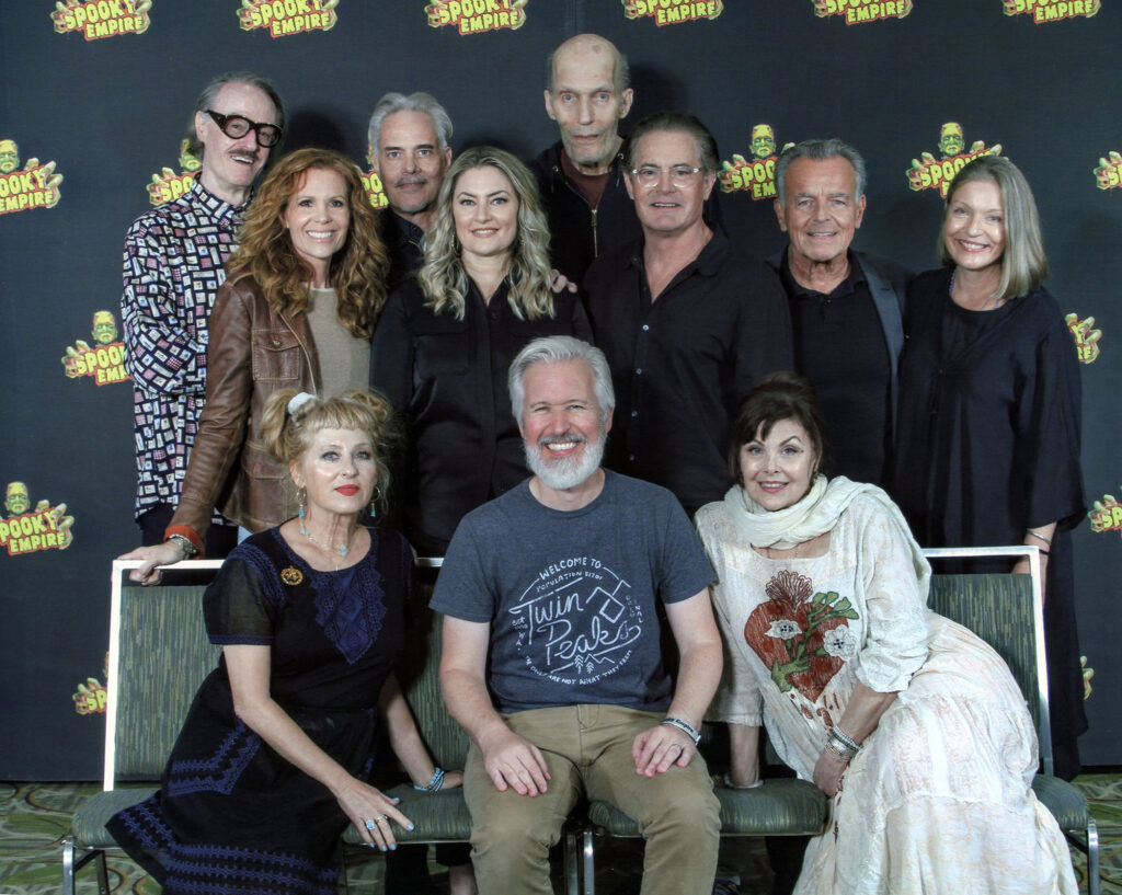 Steven sitting and surrounded by stars of Twin Peaks at Spooky Empire