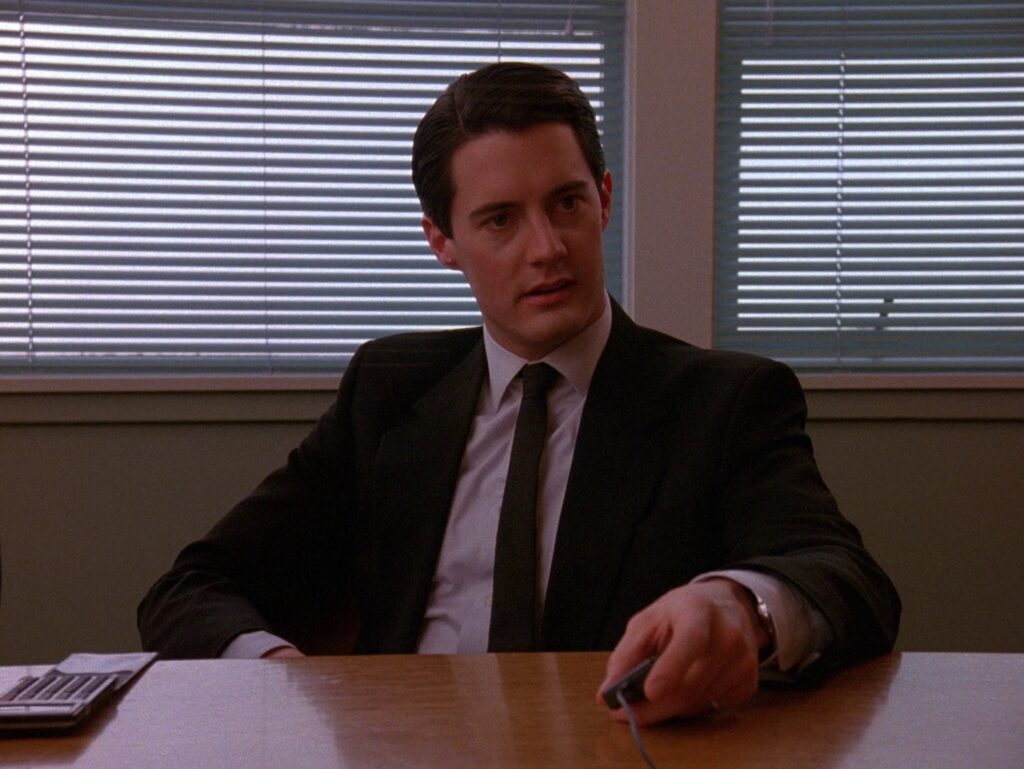 Agent Cooper sitting at a conference room table.