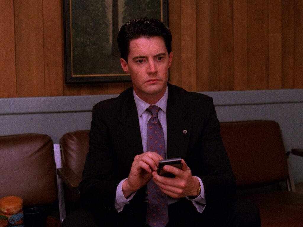 Agent Cooper sitting on a chair holding the Dial Master