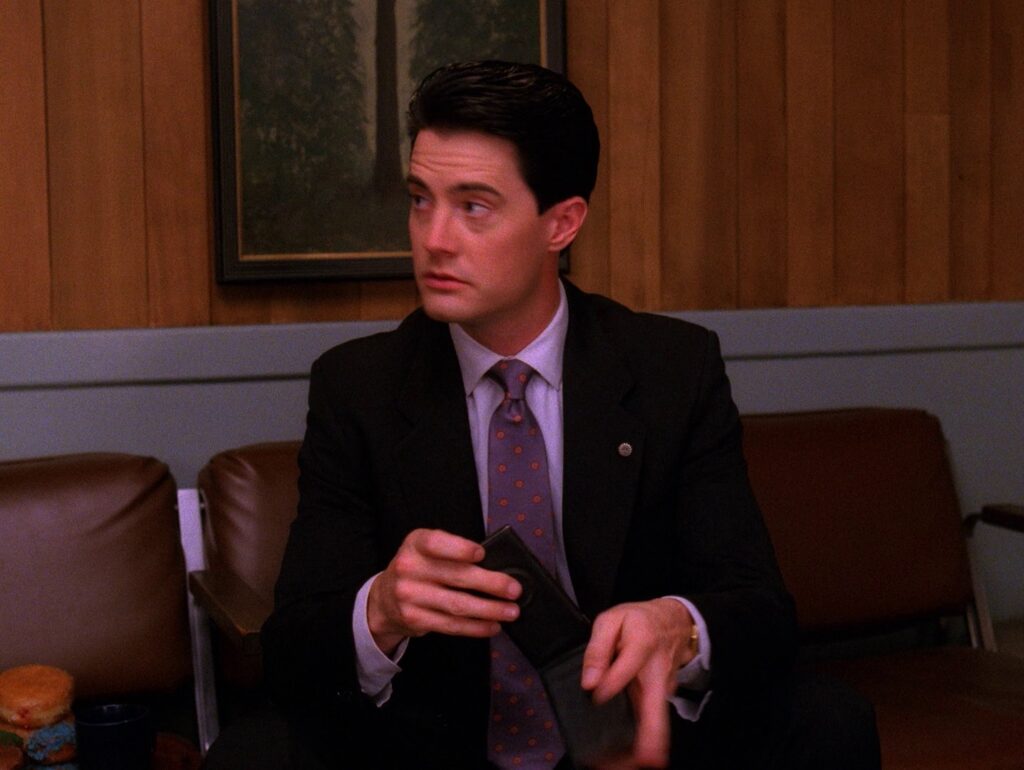 Agent Cooper sitting on a chair holding the Dial Master