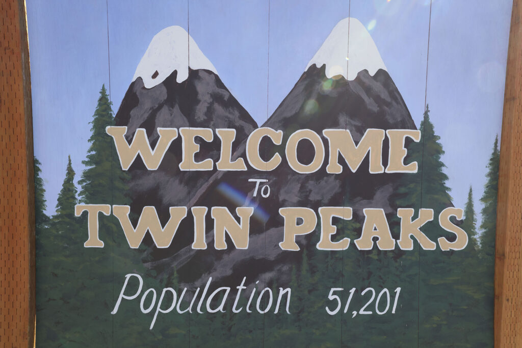 Close up of Welcome to Twin Peaks sign along side of the road