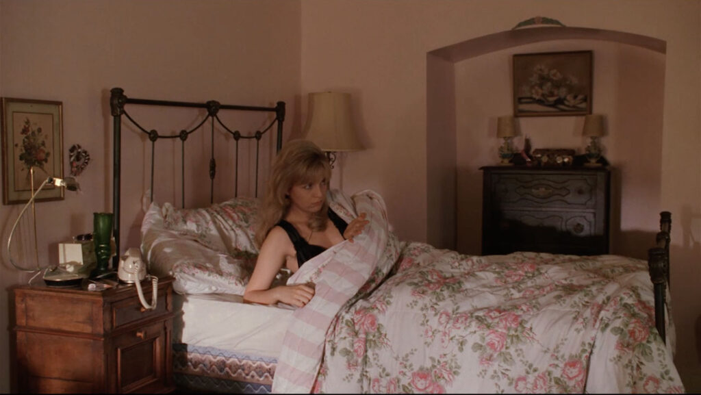 Laura Palmer sitting up in her bedroom with her hand clenched.