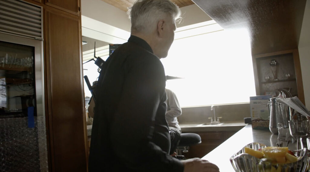 David Lynch in the kitchen looking at boxes of cereal.