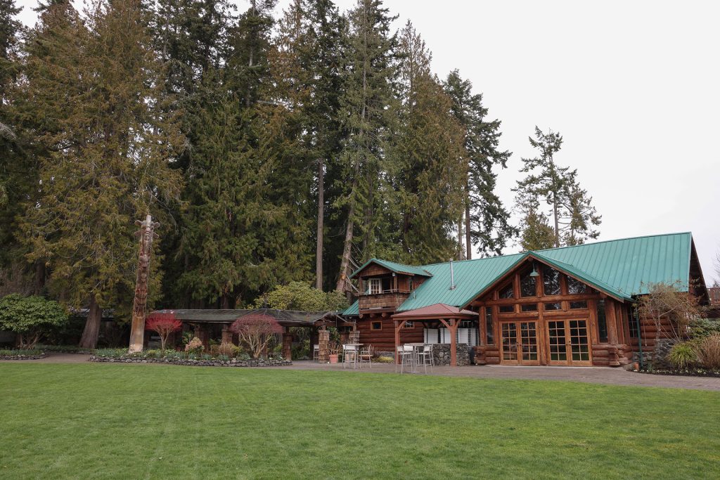 Wooden lodge with green roof under tall fir trees