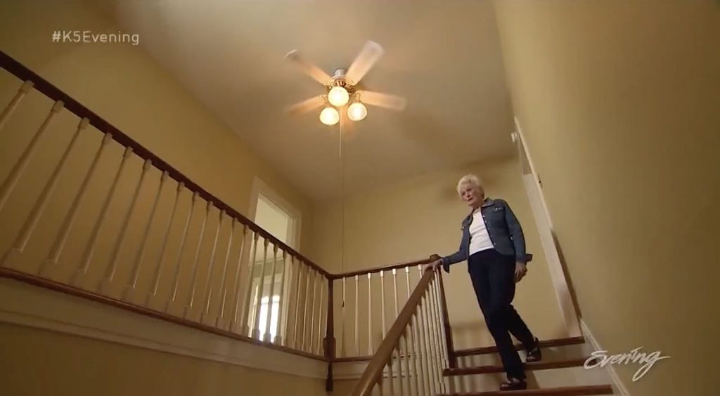 Marilyn Pettersen standing on the stairs under a white ceiling fan
