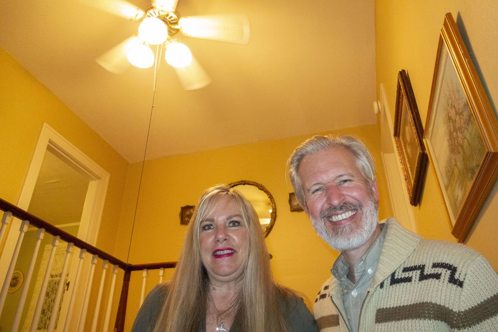Mary Reber and Steven Miller standing under the fan on the stairs to Laura's bedroom