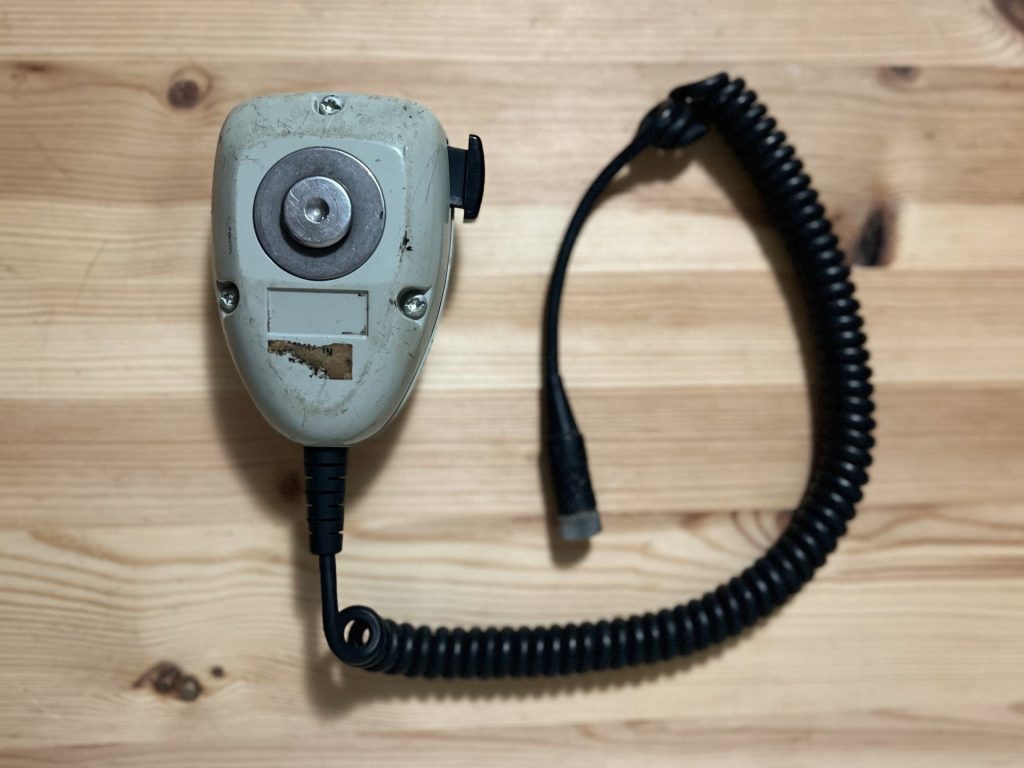 Back of Motorola hand held radio with black coil cord on wood table